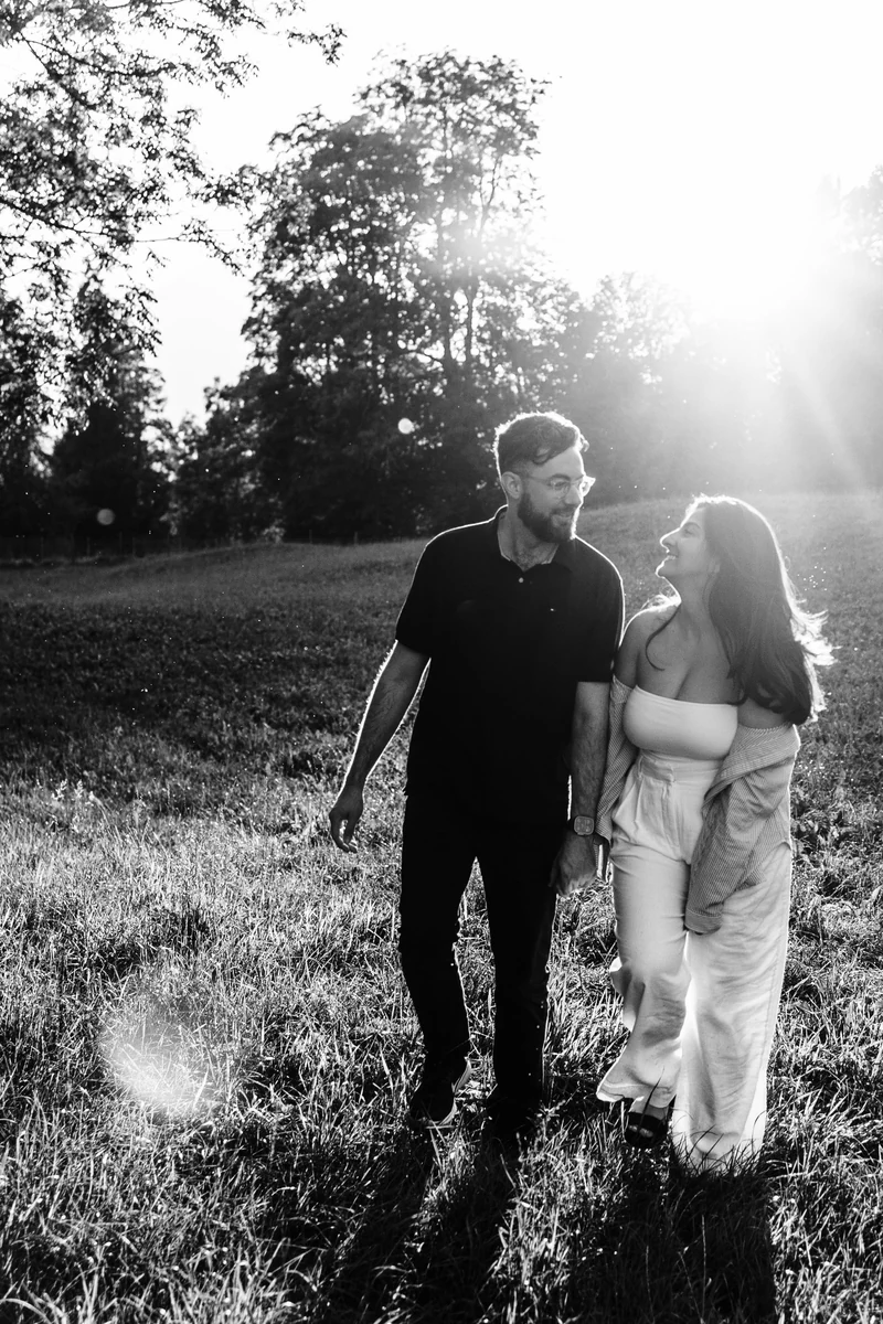 Robby walking with a companion in a sunlit field, in black and white.